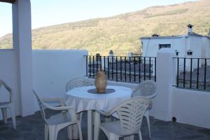 卡皮雷拉Apartamentos Rurales Rosendo: La Albahaca的阳台配有带椅子的白色桌子和花瓶