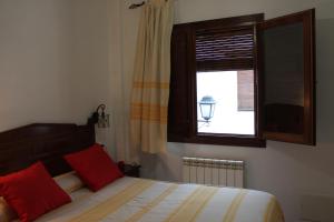 卡皮雷拉Apartamentos Rurales Rosendo: La Albahaca的一间卧室配有一张带红色枕头的床和一扇窗户