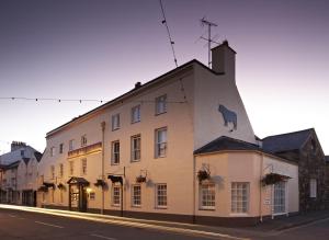 波马利斯The Bull and Townhouse, Beaumaris- The Inn Collection Group的白色的建筑,旁边是牛
