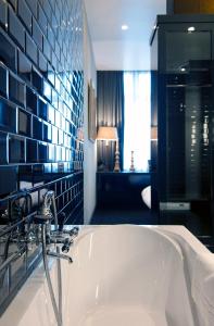 安特卫普夜之栈酒店的带浴缸的浴室和蓝色瓷砖墙