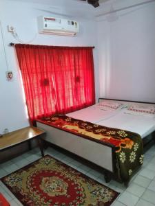 博尔普尔Chaiti Lodge - Santiniketan Bolpur的一间卧室设有两张床和红色窗帘