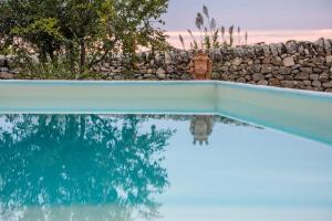 栋纳富加塔Terre di Cavalusi Relais的一座带石墙和蓝色游泳池的游泳池