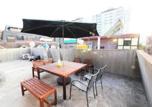 首尔GangnamStay - Foreign Female Only的屋顶上配有一张木桌和椅子及遮阳伞