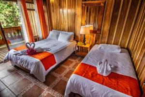 蒙泰韦尔德哥斯达黎加Cabañas Hoja Verde的一间卧室设有两张床和窗户。