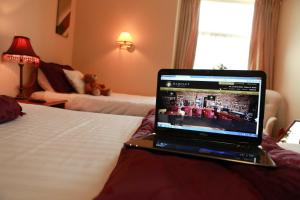 阿斯博伊Darnley Lodge Hotel的坐在酒店房间床上的笔记本电脑