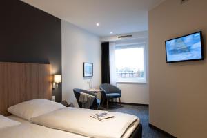 汉堡汉堡市埃贡酒店的酒店客房设有两张床、一张桌子和一台电视。