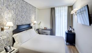 圣塞瓦斯蒂安欧洲塞尔科蒂尔酒店的酒店客房配有白色的床和电话