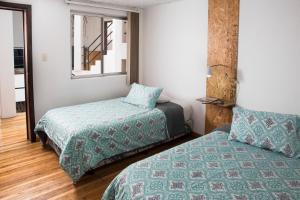 昆卡AlterNative Hostels的一间卧室设有两张床和窗户。