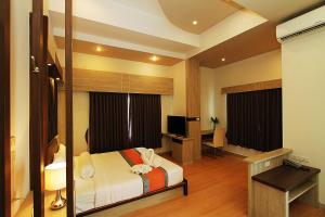 Pluak Daeng康川斯特艾酒店的一间卧室配有一张床、一张书桌和一台电视