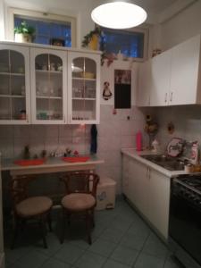 赫维兹Violetta apartmanlakás的厨房配有白色橱柜和2把凳子