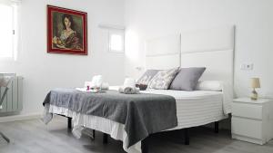 昆卡Casa Botes的一间白色卧室,配有一张床和一幅画