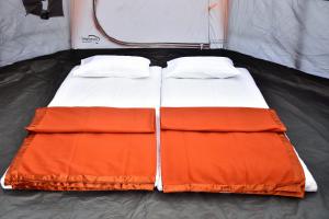 罗纳瓦拉Bombay Camping Company的帐篷内的橙色和白色床铺