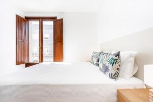 塔维拉Apartamento 1º de Maio的白色的卧室设有白色的床和窗户。
