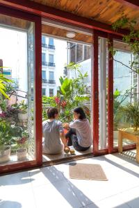 河内Hanoi Secret Garden的两个人坐在门廊上,望着窗外