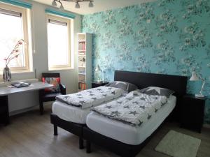 栋堡B&B De Domburcht的卧室内的两张床,配有蓝色壁纸