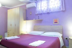 那不勒斯Campi Flegrei House的紫色卧室配有一张床和两条毛巾