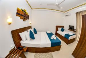 尼甘布Negombo New Queen's Palace的一间卧室配有两张带蓝白色枕头的床