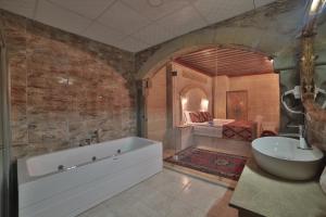 格雷梅Çakıltaşı Evi Otel的带浴缸、水槽和床的浴室