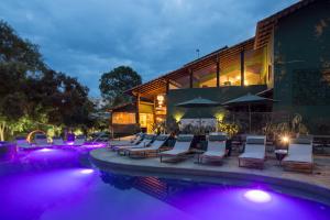 戈亚斯州上帕莱索鲁阿波萨达旅馆的一个带椅子的游泳池和一个紫色灯的建筑
