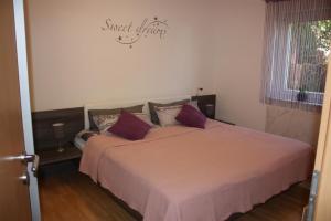 巴林根Melios的一间卧室配有一张带紫色枕头的大床
