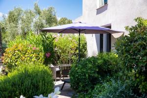 圣特罗佩Hotel le Mandala的一个带遮阳伞和椅子及灌木的庭院
