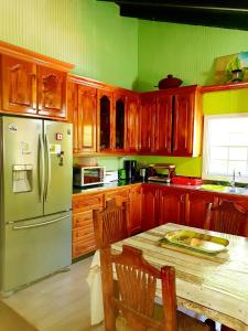 格罗斯岛Seawind Cottage- Traditional St.Lucian Style的厨房配有木制橱柜和1张带冰箱的桌子。