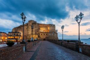 那不勒斯Napoli Storia e Mare的黄昏时坐在海边的大型城堡