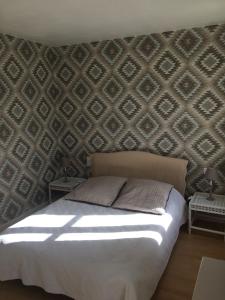 Saint-Pol-sur-Ternoise拉法姆杜博基努阿酒店的一间卧室配有一张床和一堵图案墙