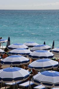 尼斯Très bel appartement vue mer à Nice的海滩上的蓝白遮阳伞