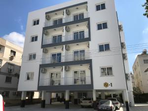 北尼科西亚Cozy Flat in the heart of North Nicosia --- 55-1的一座白色的建筑,前面有汽车停放