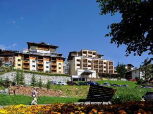 瑟弗浩斯加尼阿尔卑具维尔酒店的穿过公园的人,有长凳和建筑物