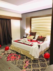 达曼Ramada by Wyndham Dammam Khaleej Road的卧室配有一张铺有红色鲜花的大床,位于地板上