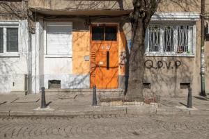 索非亚Feel Sofia - one bedroom apartment next to Russian Square的树旁有橙色门的建筑