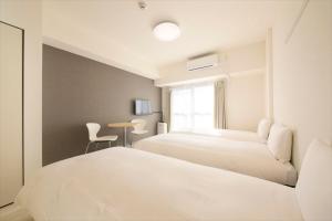 浦安Bay Hotel Urayasu-ekimae的酒店客房设有两张床和一张桌子。