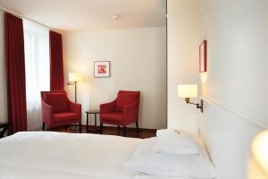 苏黎世Boutique Hotel Helmhaus Zürich的一间酒店客房,配有两张红色椅子和一张床