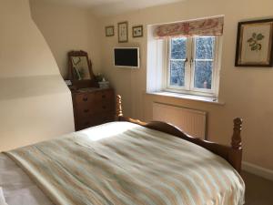 赛伦塞斯特The Long House的一间卧室配有带梳妆台和窗户的床。