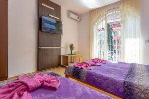 索科矿泉村Guesthouse Sunny的一间卧室配有两张紫色床单和一台电视。