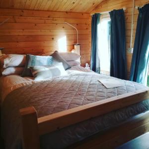 CarrigansDunmore Gardens Log Cabins的一间卧室配有一张带蓝色窗帘的大床