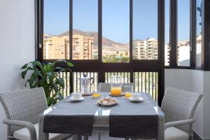 洛斯克里斯蒂亚诺斯Almar Apartamento en Los Cristianos con AC的一张桌子、两把椅子和一张桌子,上面放着橙汁