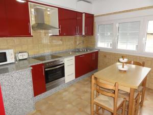 科尔库维翁Casa Lourdes的厨房配有红色橱柜和木桌