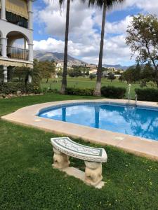 福恩吉罗拉La Siesta de Mijas Golf 174的一座游泳池,旁边设有长凳