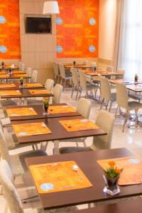 库里提巴Rio Hotel by Bourbon Curitiba Batel的用餐室配有桌椅和橙色墙壁