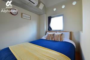 高松Alphabed TakamatsuKawaramachi 501 / Vacation STAY 21604的一间卧室配有一张带蓝色床单的床和一扇窗户。