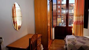 莱昂桑多瓦尔旅馆的一间卧室配有一张床、一张桌子和一面镜子