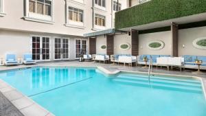 洛杉矶Mosaic Hotel Beverly Hills的一座带蓝色椅子的游泳池和一座建筑