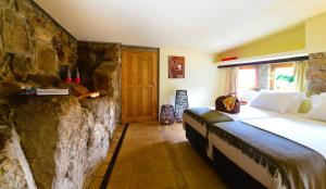 拜昂Casas de Pousadouro的一间卧室设有一张大床和石墙