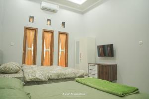 日惹M Stay Guest House Jogja的一间带两张床的卧室和一台电视