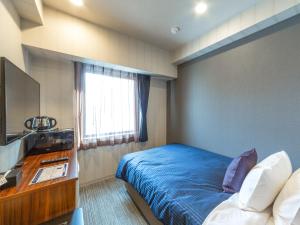 札幌HOTEL LiVEMAX Sapporo Susukino的一间卧室配有一张床、一张书桌和一台电视