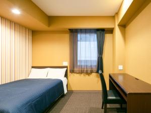 仙台HOTEL LiVEMAX Sendai Aobadori的一间卧室配有一张床、一张书桌和一个窗户。