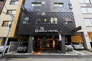 水原市Malu Hotel Suwon的停车场内停放车辆的酒店入口